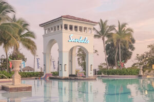 Sandals branded white bell tower style gazebo directly behind a blue water swimming pool